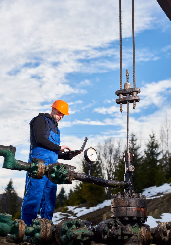 petroleum engineer using laptop in oil field.